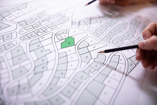 close-up-of-human-hand-holding-pencil-over-paper-cadastre-map