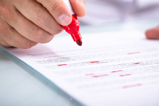 Close-up Of A Businessperson's Hand Holding Marker On Document